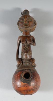 une petite statue représentant un homme assis sur un vase