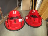 Deux autos tamponneuses rouges sont garées sur le sol d'un garage.
