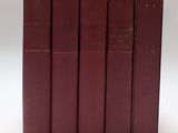 cinq livres rouges sont alignés sur une surface blanche