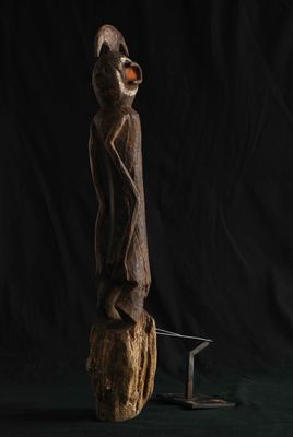 une sculpture en bois représentant un homme debout sur un morceau de bois