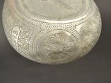 a silver vase with a design on it on a table