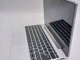 a silver laptop with a black keyboard on a white surface