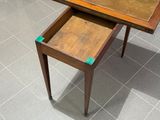 une petite table avec un tiroir en dessous, posée sur un sol carrelé