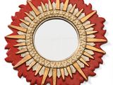 un miroir rouge et doré à rayons de soleil accroché à un mur blanc