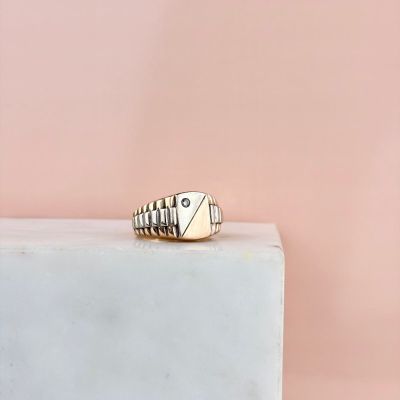 une chevalière en or sertie d'un diamant, posée sur un bloc de marbre