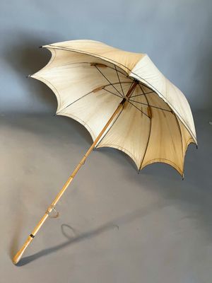 a white umbrella with a wooden handle on a gray surface