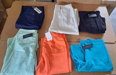 Plusieurs paires de pantalons sont disposées sur une boîte en carton