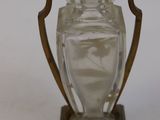a glass vase on a wooden stand on a white surface