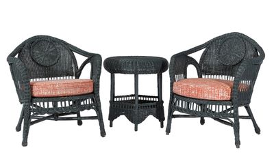 two black wicker chairs and a small table with a red cushion