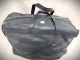 a grey bag with a black handle on a white background