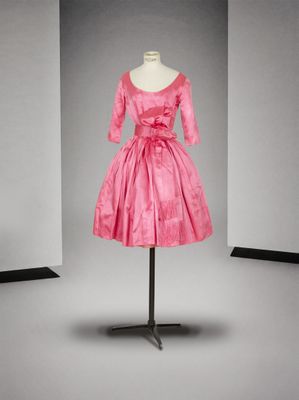 une robe rose posée sur un mannequin devant un fond gris