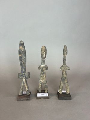trois statues en pierre représentant un homme et une femme, posées sur une table