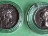 two silver coins in plastic cases on a green surface