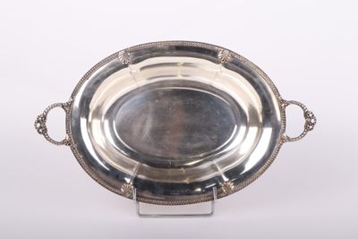un plat ancien en argent posé sur un socle et entouré d'une chaîne