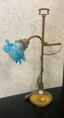 lampe en laiton plaqué avec un abat-jour en verre bleu, posée sur une table noire