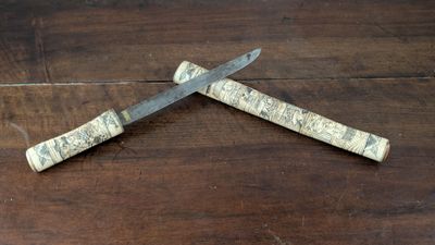 two knives on a wooden table with a piece of wood