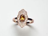 un gros plan d'une bague sertie d'un saphir jaune entouré de diamants blancs
