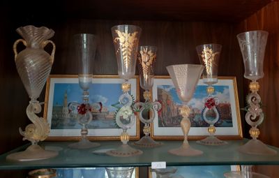 Plusieurs vases en verre et des tableaux sont posés sur une étagère dans un meuble.