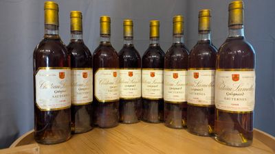 six bottles of wine are lined up on a wooden barrel