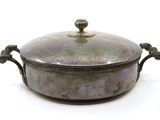 une casserole en argent avec un couvercle, posée sur une surface blanche