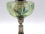 une lampe à huile ancienne en argent et verre vert sur fond blanc