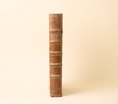 un vieux livre posé sur une table à côté d'un mur blanc