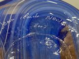 a blue glass vase with writing on it on a table