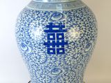 un vase bleu et blanc muni d'un couvercle en bois, posé sur un socle