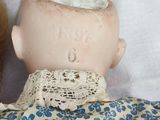 a doll that is laying next to a doll that is wearing a blue and white dress
