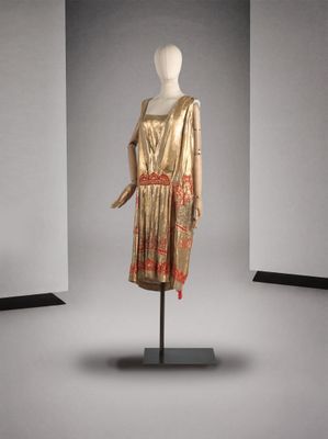 une photo d'un mannequin portant une robe dorée avec une ceinture rouge