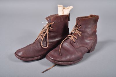 une paire de bottes en cuir marron à lacets, d'où dépasse un os