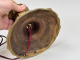 a hand that is holding a wooden object with a red cord