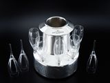 a silver ice bucket with glasses in it on a black surface