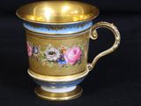 a gold cup with blue and pink flowers on it
