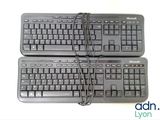 two black keyboards sitting next to each other on a white surface