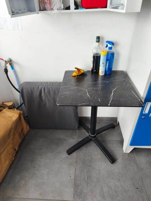une petite table sur laquelle se trouve une bouteille de produit nettoyant, dans un coin de la pièce