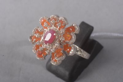 une image représentant une bague ornée d'une pierre rose entourée de pierres orange