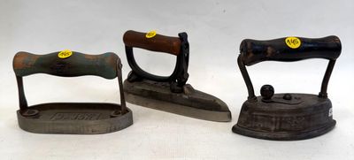 trois objets anciens en fonte posés sur un plan de travail blanc