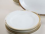 several white plates with gold rims are stacked on top of each other