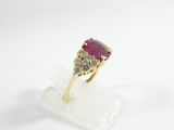 a close up of a gold ring with a ruby stone and diamonds
