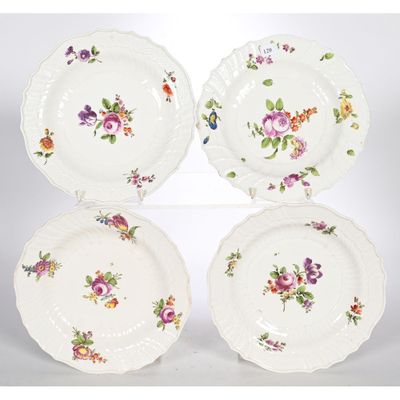 quatre assiettes ornées de motifs floraux, posées sur une surface blanche