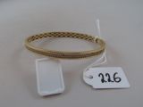un bracelet en or et un téléphone portable posés sur une table blanche