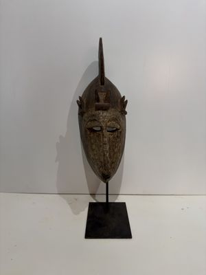an image of a wooden mask on a stand on a white surface