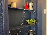 a shelf with a potted plant on it in the corner of a room