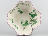 a white bowl with green flowers on it on a stand