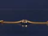 a close up of a gold tie bar on a blue surface