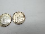 two silver coins sitting side by side on a white surface