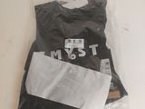 un t-shirt noir posé sur une table blanche, à côté d'une paire de ciseaux et d'une paire de ciseaux