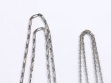 two pieces of silver chain on a white surface
