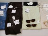 four pairs of jeans and a pair of sunglasses sit on a table